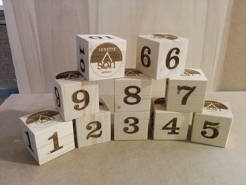 Serie de cubos de madera con números de mesa y logotipo grabados con láser